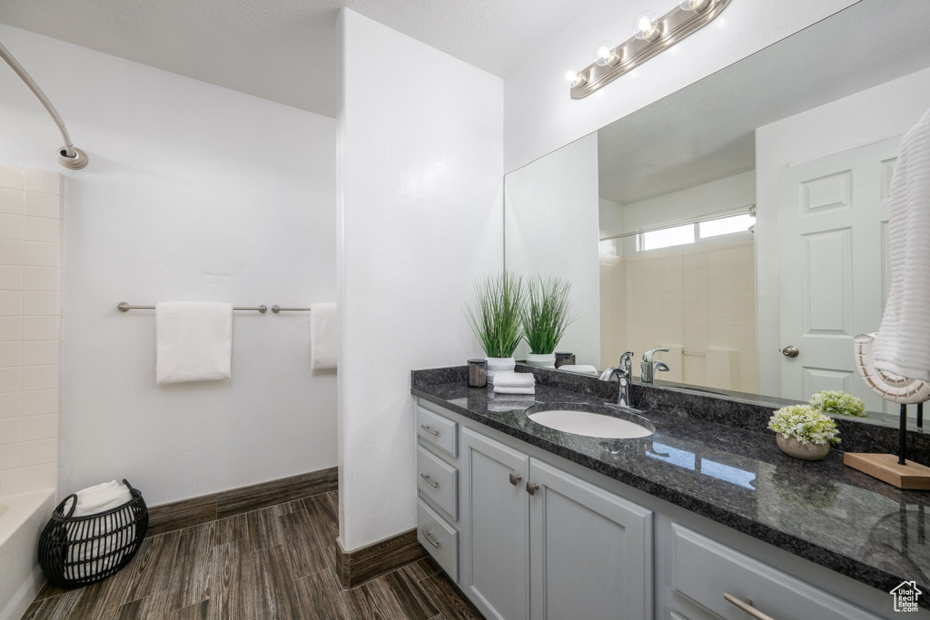 Full bathroom with vanity, wood finished floors, and washtub / shower combination