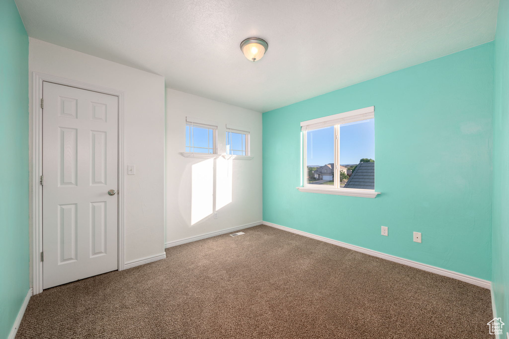 Empty room featuring carpet floors and plenty of natural light