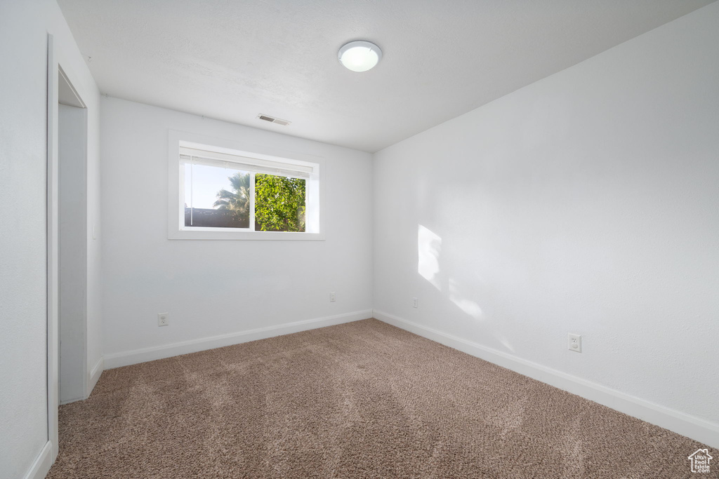 Carpeted spare room featuring baseboards