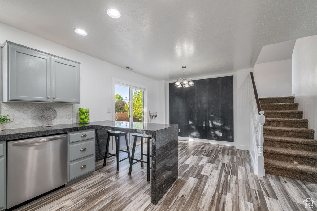 Kitchen with dishwasher, gray cabinetry, a peninsula, wood finished floors, and recessed lighting