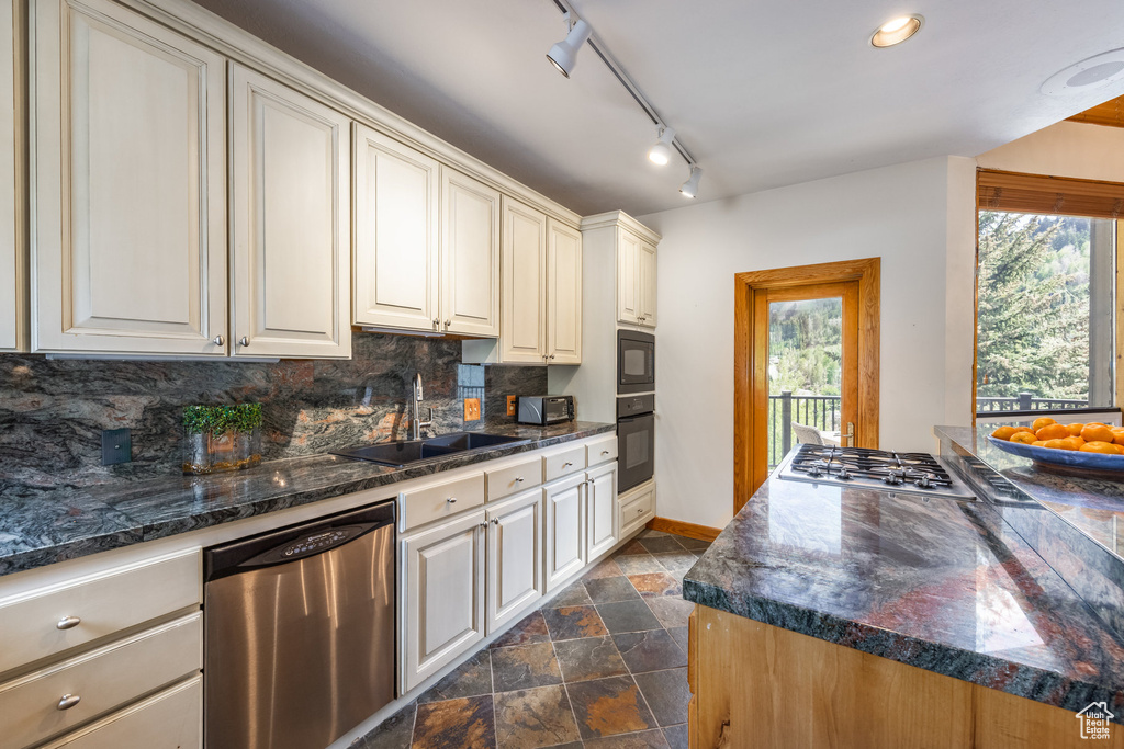 Kitchen featuring stainless steel appliances, dark stone finish flooring, and decorative backsplash