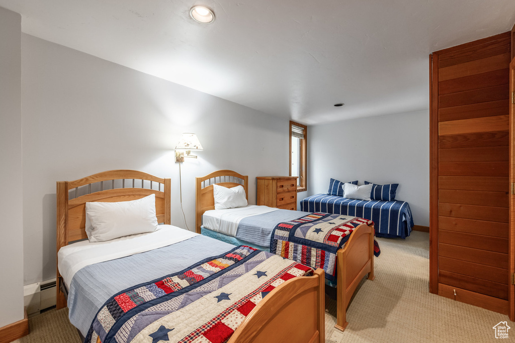 Bedroom featuring light carpet, baseboard heating, and recessed lighting