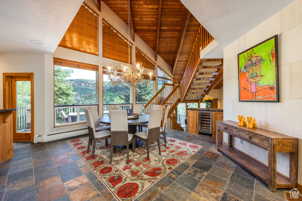 Dining space with stone tile flooring, wine cooler, a chandelier, a baseboard heating unit, and wooden ceiling