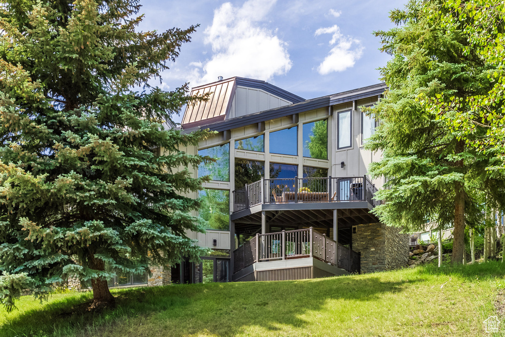 Rear view of house featuring a yard and stone siding
