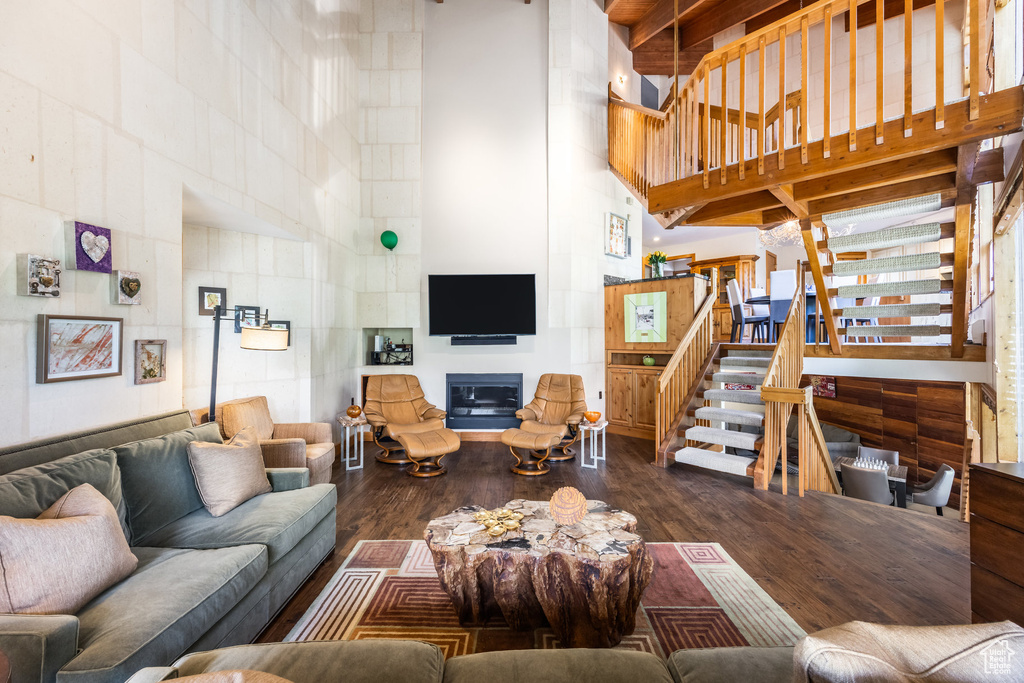 Living area featuring a towering ceiling, wood finished floors, and stairs