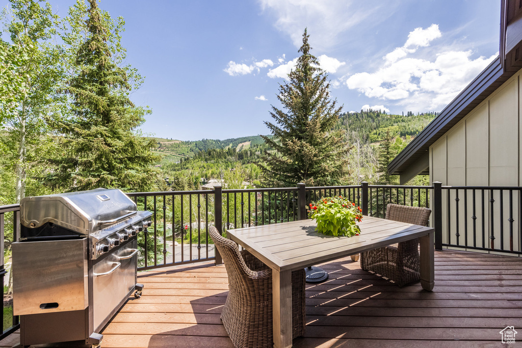 Deck with a grill, outdoor dining area, and a wooded view