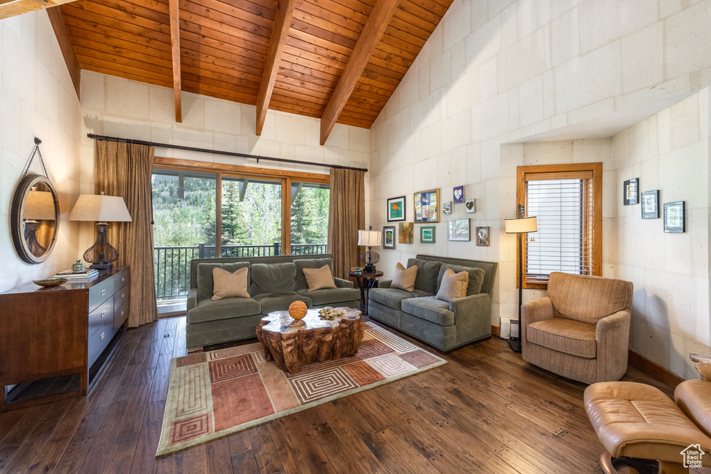 Living area featuring dark wood-style floors, high vaulted ceiling, a wooden ceiling with exposed beams, and plenty of natural light
