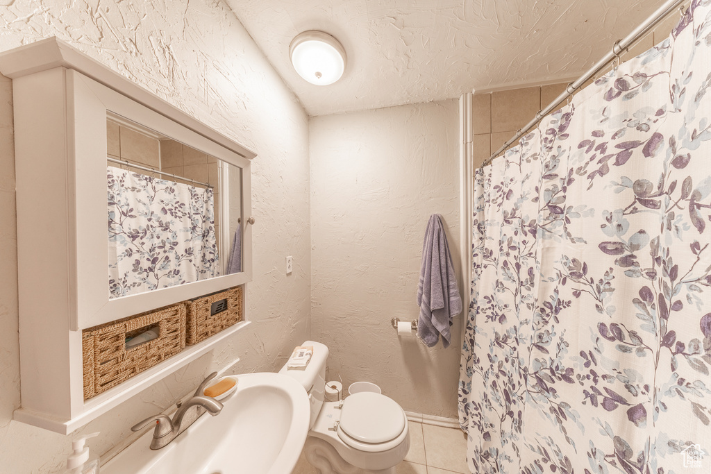 Bathroom featuring tile patterned floors, a shower with curtain, a textured wall, and a textured ceiling