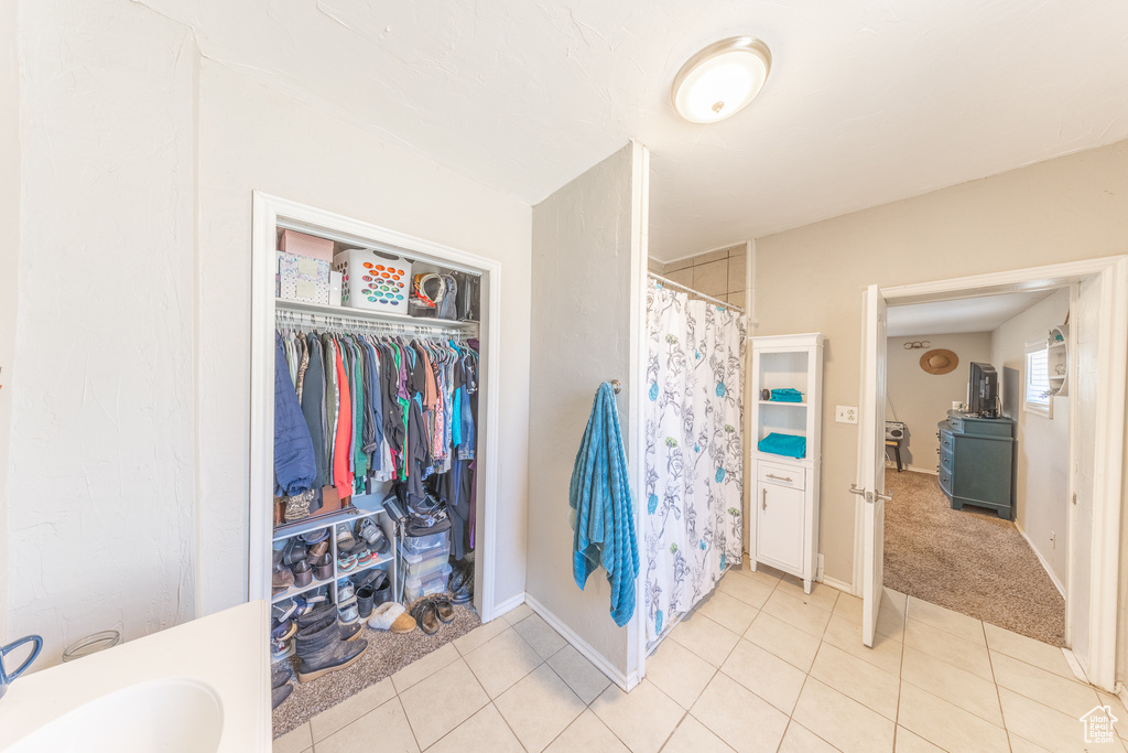 Full bath with tile patterned flooring, curtained shower, and a walk in closet