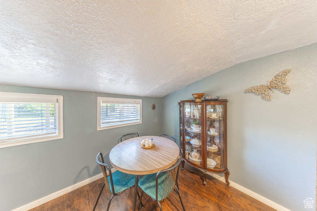 Dining area featuring a textured ceiling, wood finished floors, and lofted ceiling