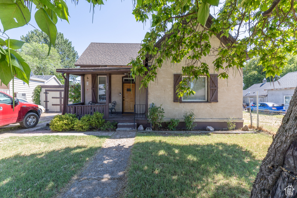 View of front facade featuring a porch, a shingled roof, and stucco siding
