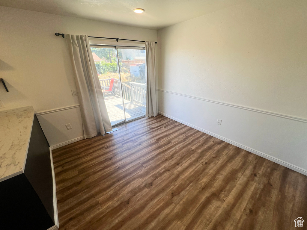 Unfurnished room featuring baseboards and dark wood-style flooring