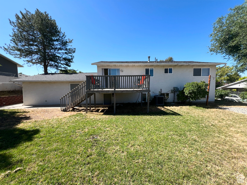 Back of house featuring stairs, stucco siding, a wooden deck, and a yard