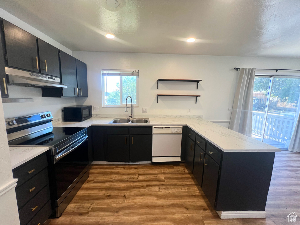 Kitchen featuring white dishwasher, stainless steel range with electric cooktop, under cabinet range hood, a peninsula, and black microwave
