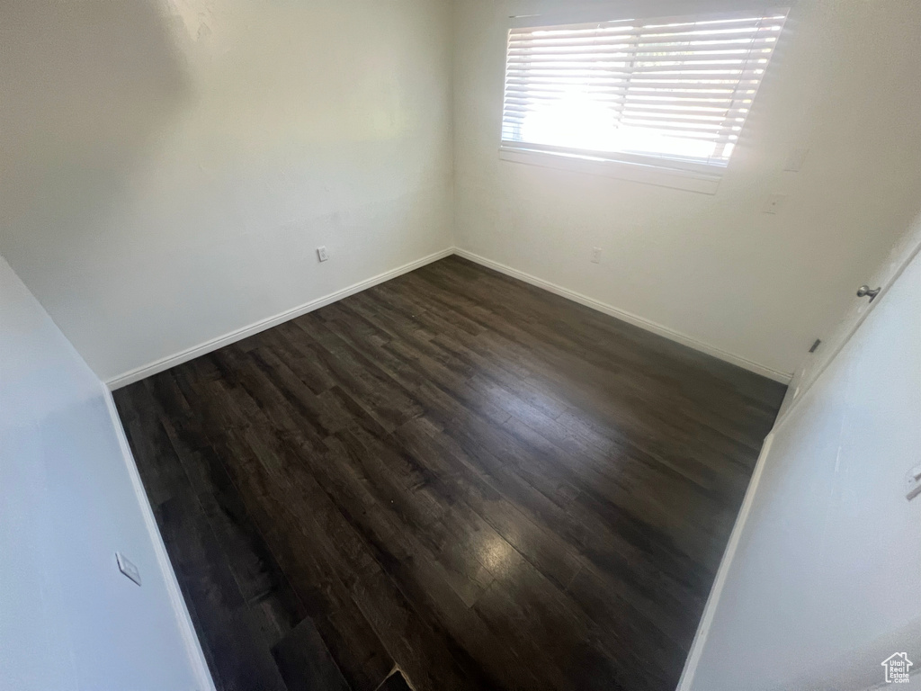 Spare room featuring dark wood finished floors and baseboards