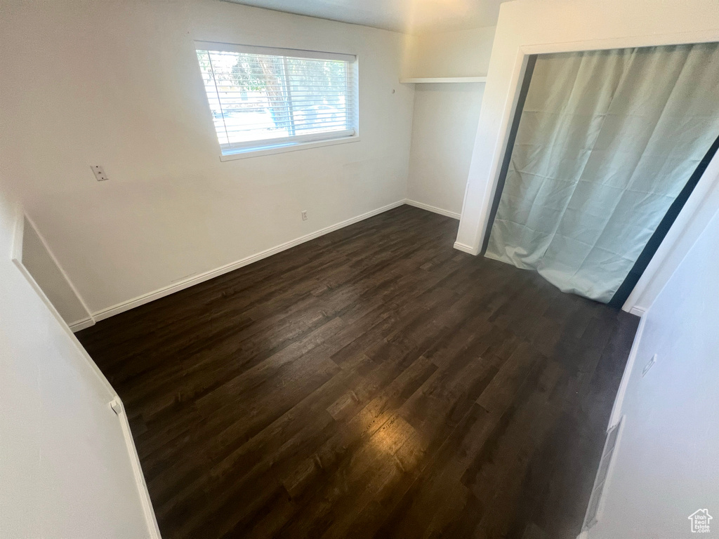 Unfurnished bedroom with dark wood-style floors and baseboards