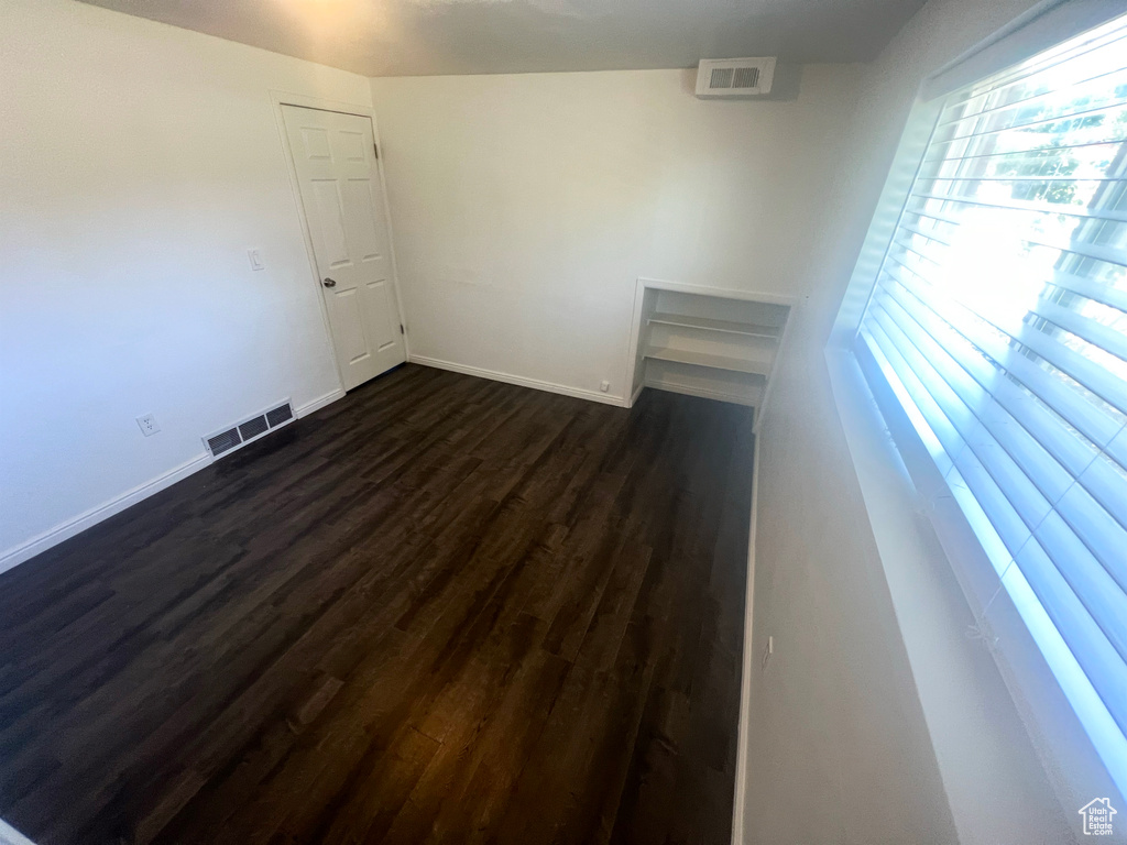 Spare room with dark wood-style flooring and baseboards