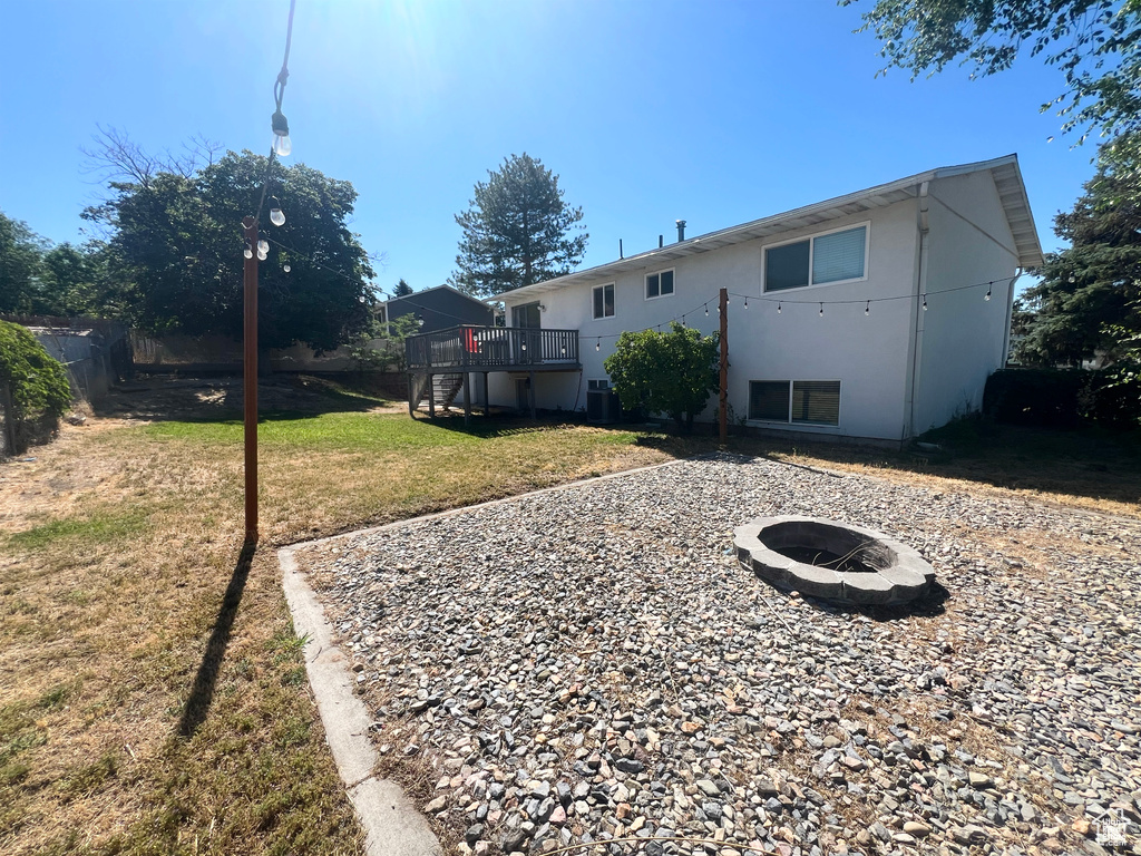 Back of house featuring a fire pit, a wooden deck, stairway, and stucco siding