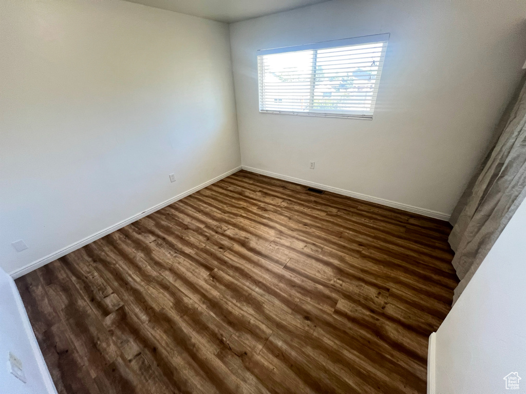 Empty room with dark wood-style floors and baseboards
