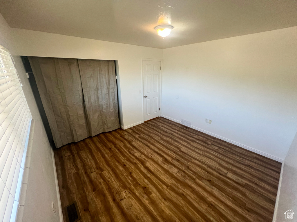 Unfurnished bedroom featuring dark wood finished floors and a closet
