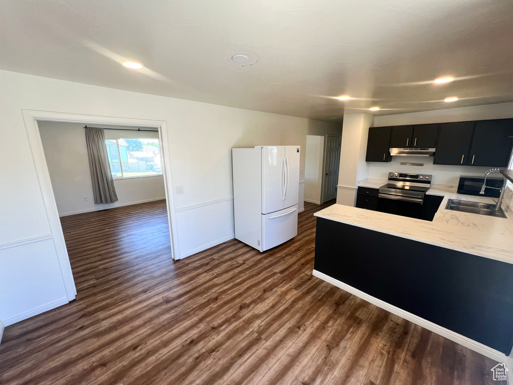 Kitchen with freestanding refrigerator, stainless steel range with electric cooktop, dark cabinets, dark wood-type flooring, and a peninsula