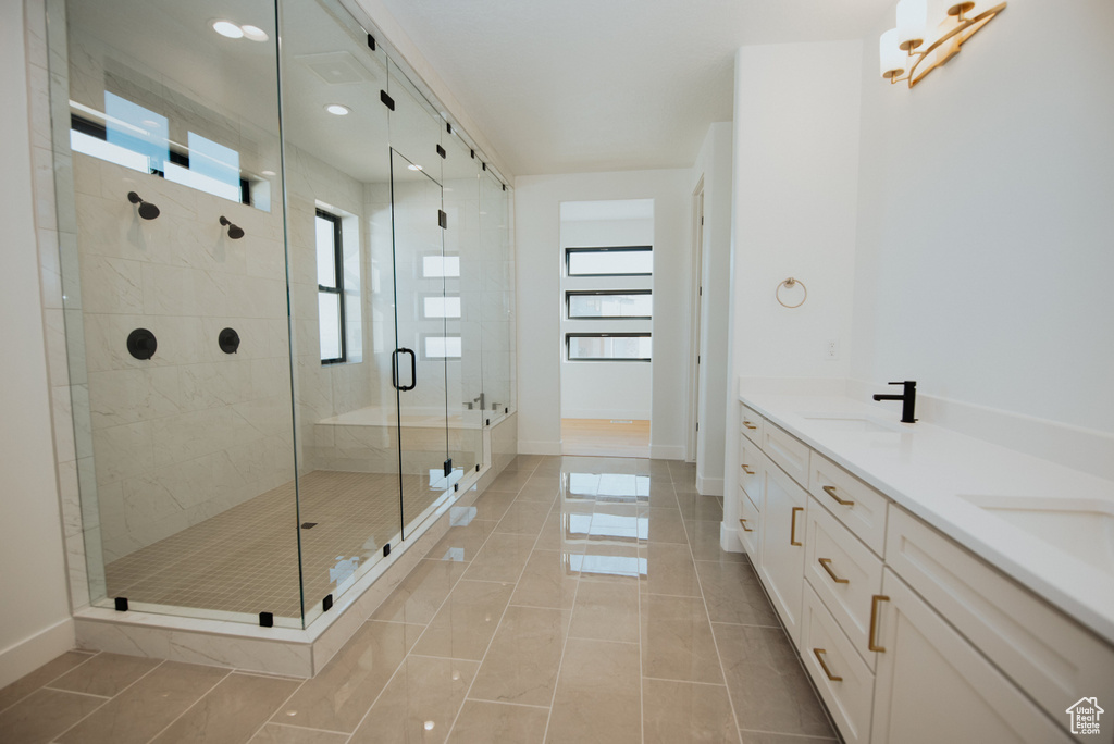 Bathroom with a shower stall, double vanity, and tile patterned floors
