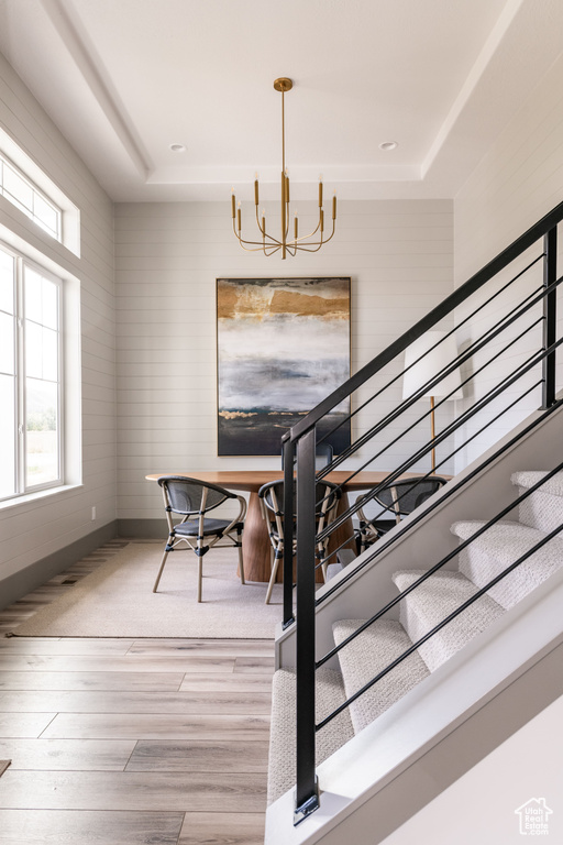 Stairs featuring a chandelier, wood finished floors, plenty of natural light, a raised ceiling, and recessed lighting