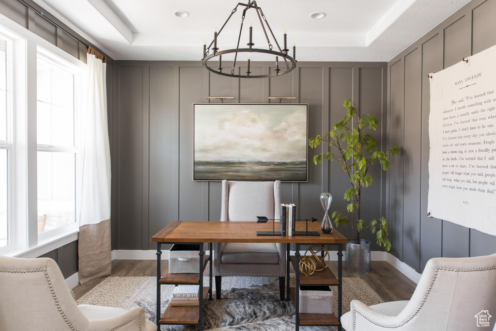 Office with wood finished floors, a decorative wall, a chandelier, and a raised ceiling