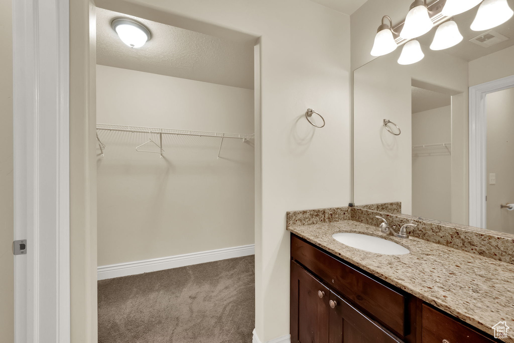 Bathroom featuring vanity and a walk in closet