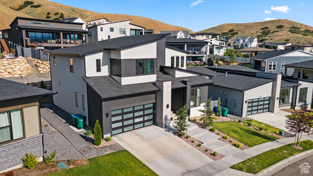 Contemporary home featuring driveway, a mountain view, a residential view, and roof with shingles