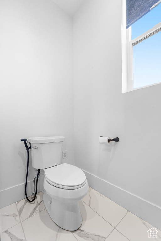 Bathroom with marble look tile flooring and toilet