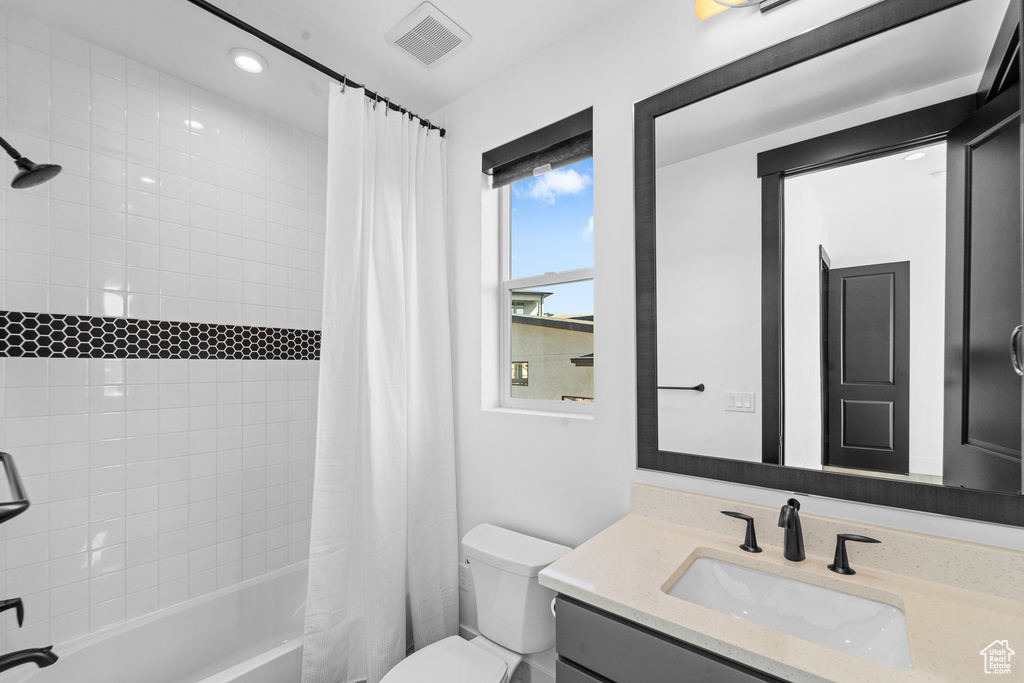 Bathroom featuring vanity, shower / bath combo, and recessed lighting