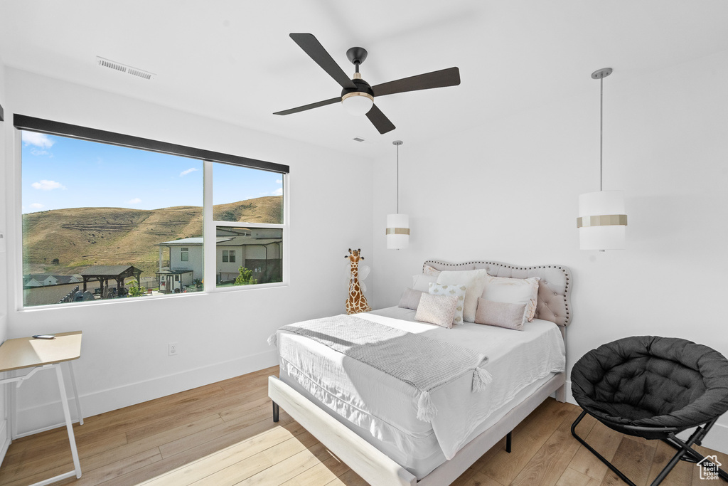 Bedroom with wood-type flooring, a mountain view, and a ceiling fan