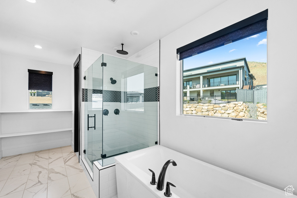 Bathroom with a soaking tub, a shower stall, marble finish flooring, and recessed lighting