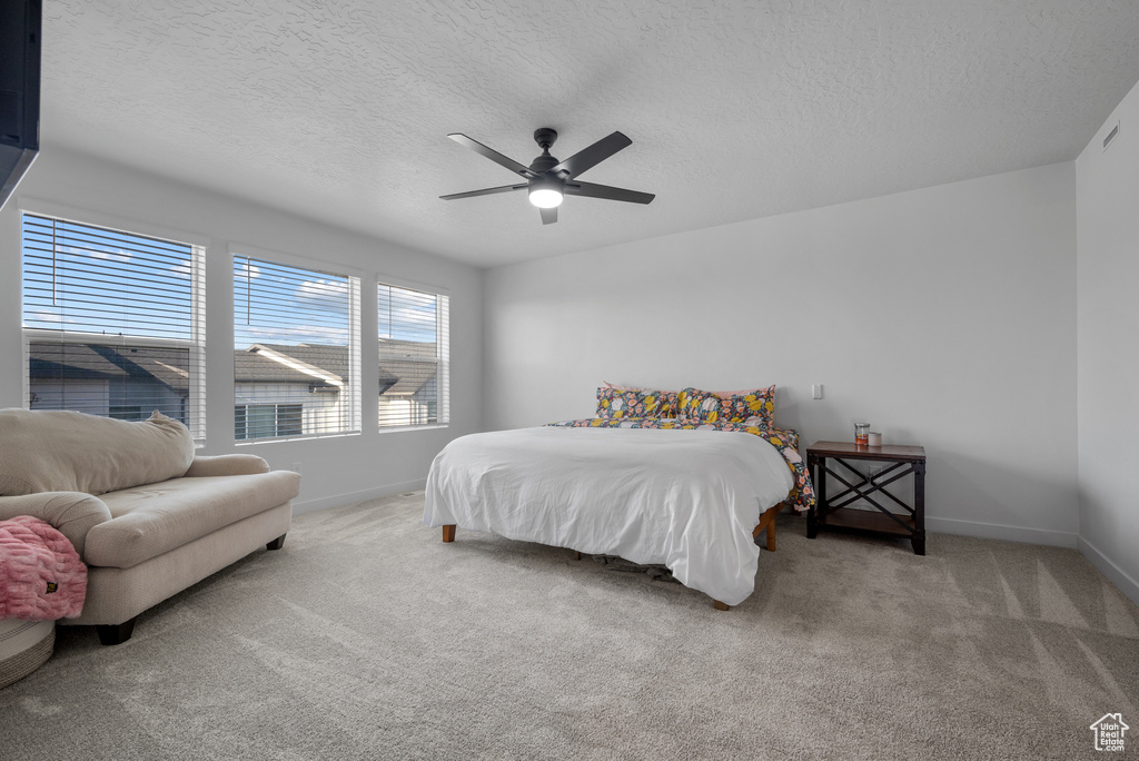 Bedroom with carpet floors, a textured ceiling, and ceiling fan