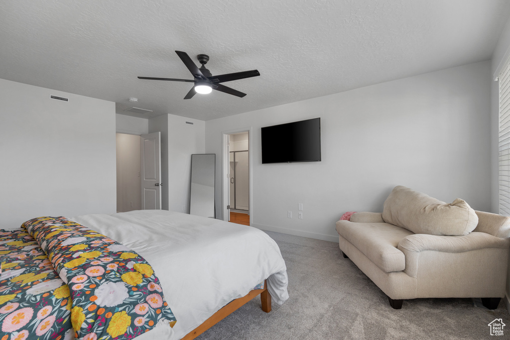 Carpeted bedroom featuring a ceiling fan and a textured ceiling