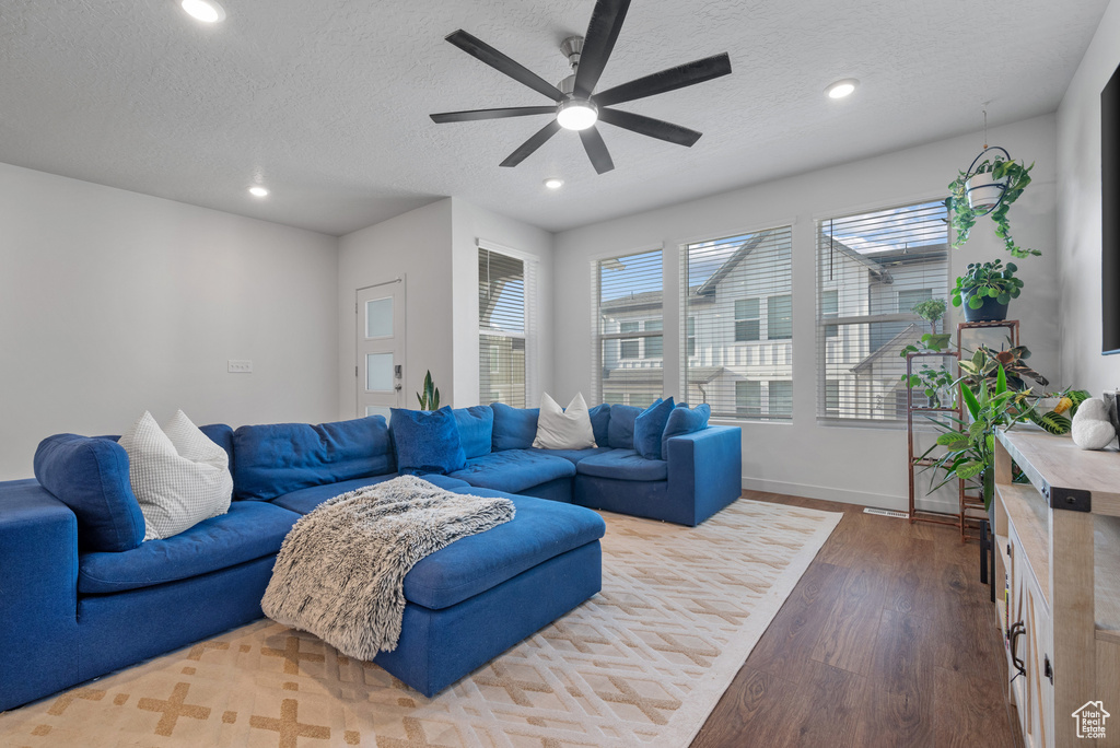 Living room featuring dark wood finished floors, a ceiling fan, recessed lighting, and a textured ceiling