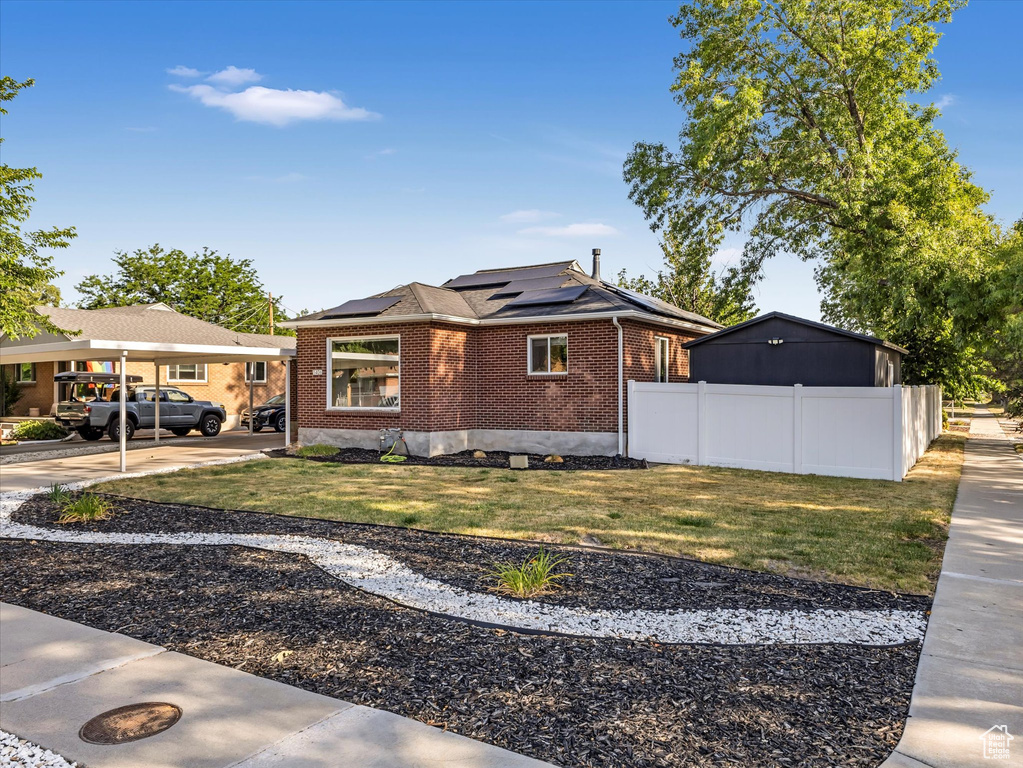 View of front facade featuring brick siding and roof mounted solar panels