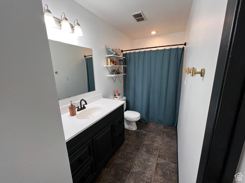 Bathroom featuring vanity, stone finish flooring, and curtained shower