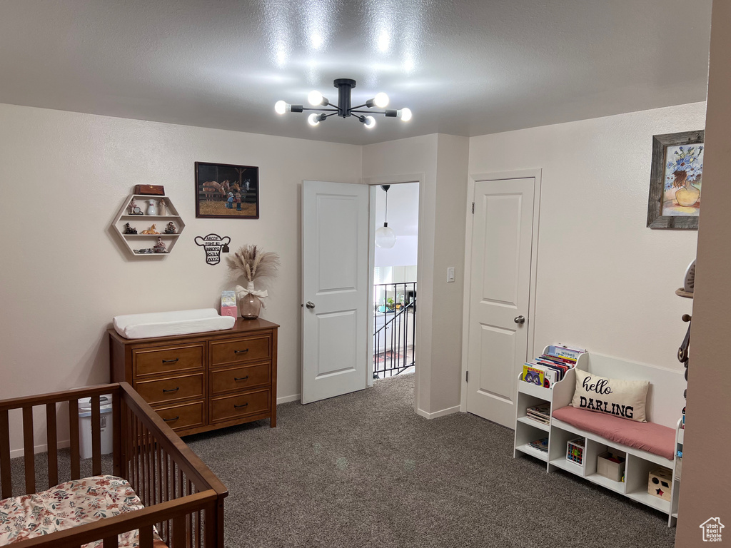 Bedroom with a chandelier, a crib, and dark colored carpet