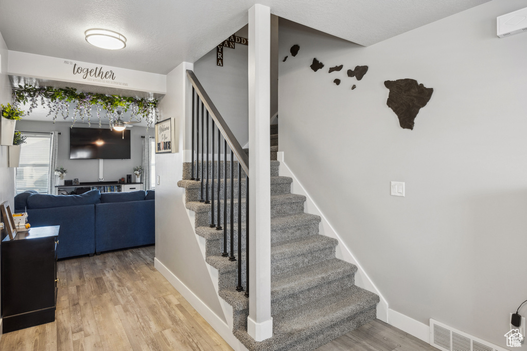 Stairway with wood finished floors and baseboards