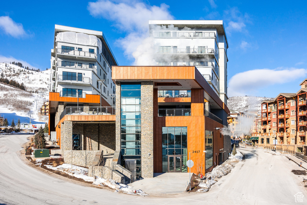 Snow covered building featuring a mountain view and a view of apartment building / complex