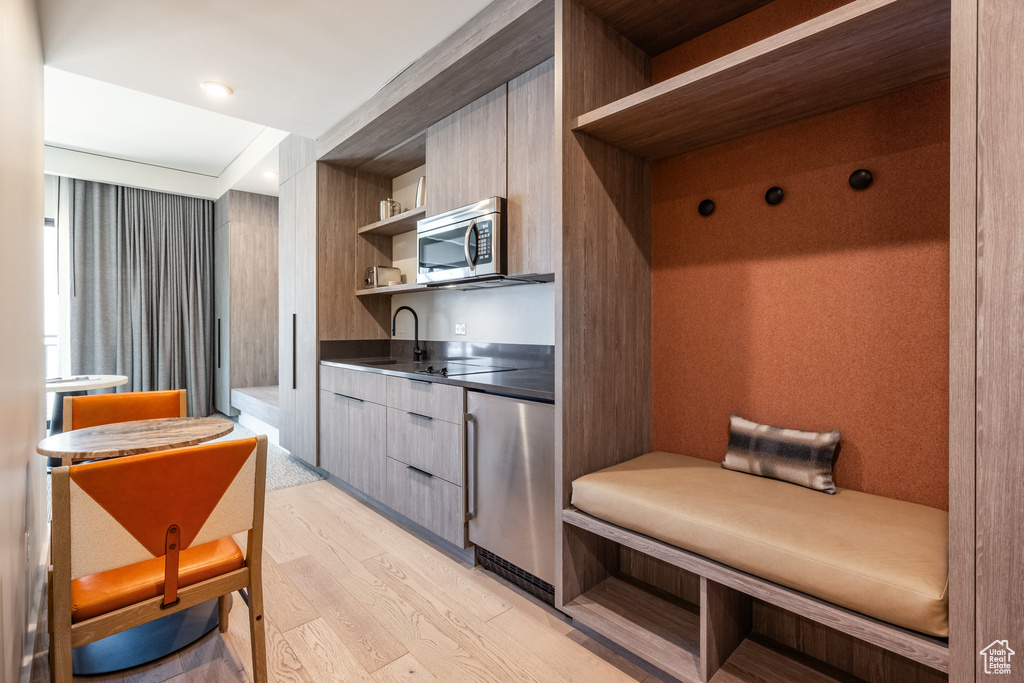Kitchen featuring open shelves, stainless steel microwave, modern cabinets, refrigerator, and light wood finished floors
