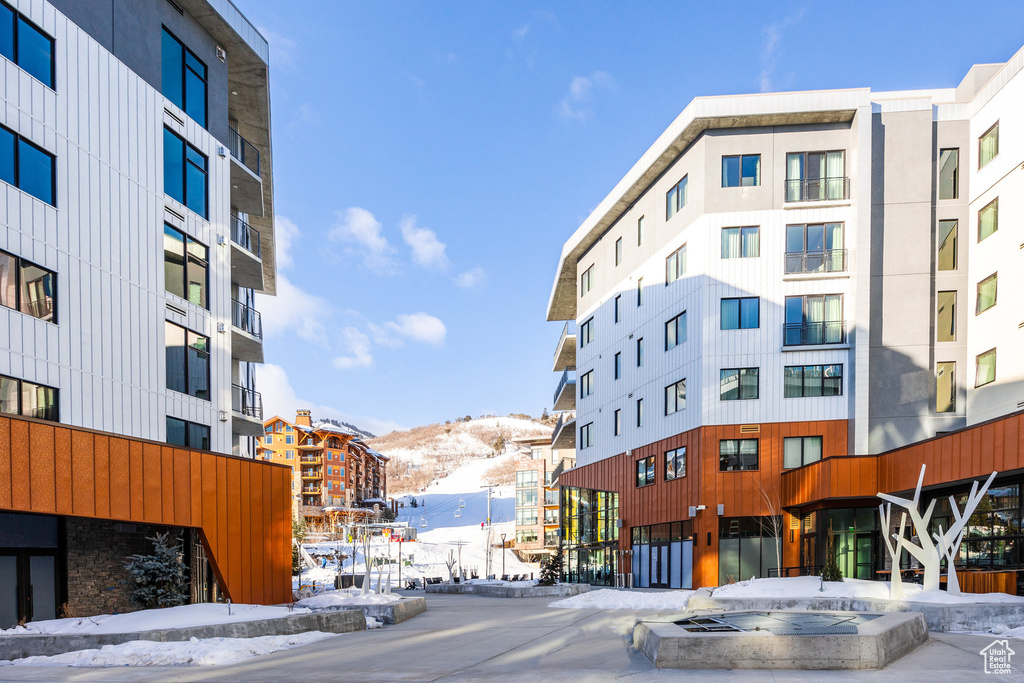 Snow covered building featuring a mountain view and a view of apartment building / complex