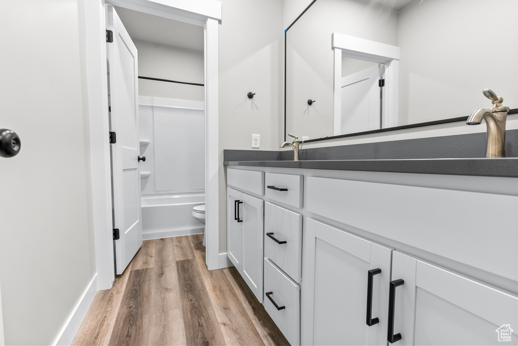 Bathroom with vanity, wood finished floors, and shower / tub combination