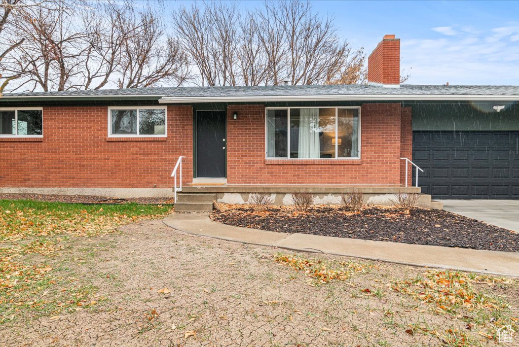 Ranch-style home featuring entry steps, brick siding, driveway, and a chimney