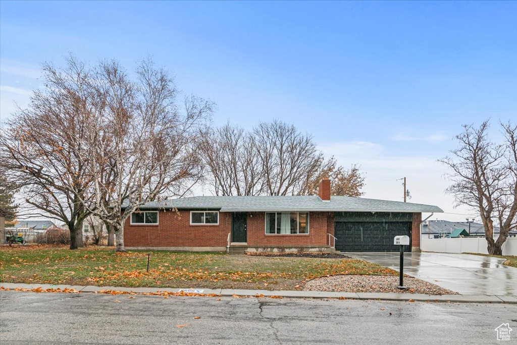 Ranch-style home featuring brick siding, concrete driveway, a chimney, and a garage