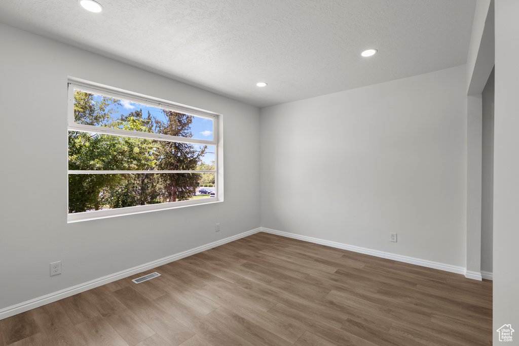 Spare room featuring wood finished floors, recessed lighting, and a textured ceiling