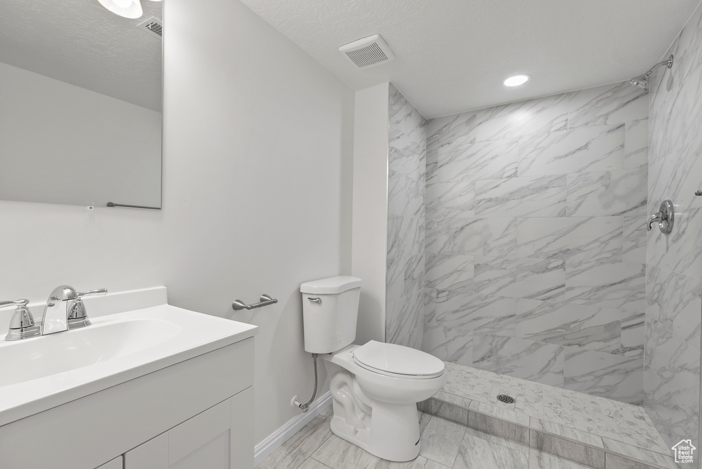 Full bathroom featuring vanity, a marble finish shower, marble finish flooring, recessed lighting, and a textured ceiling
