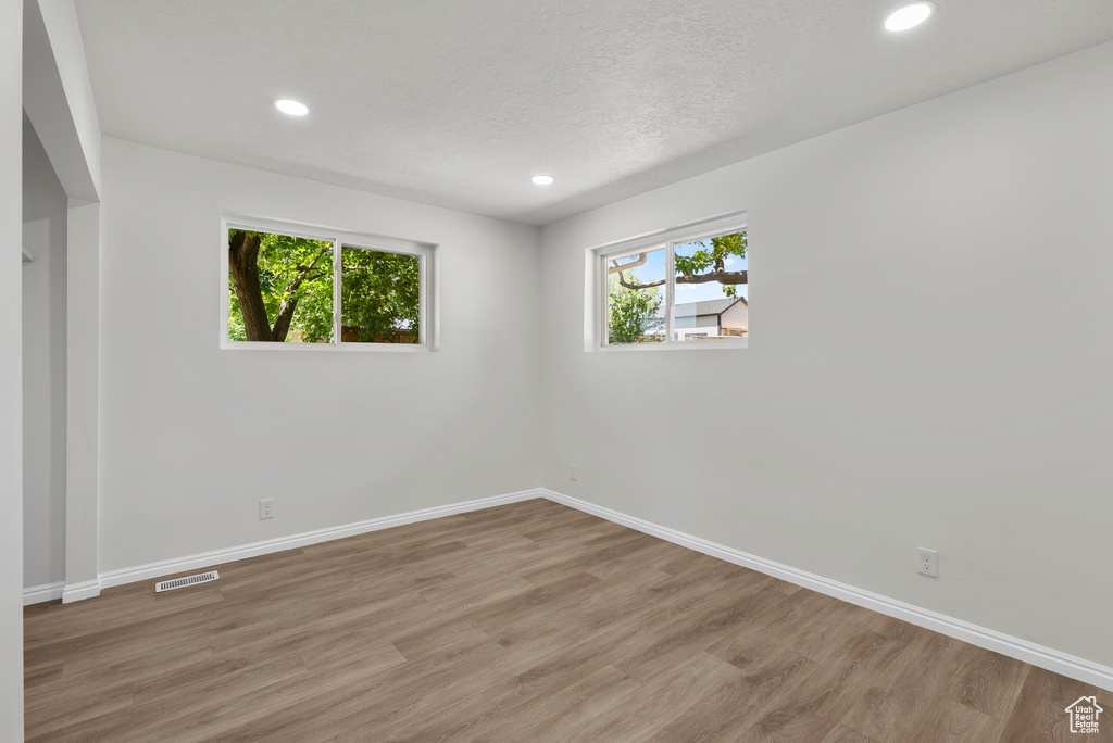 Unfurnished room with wood finished floors and recessed lighting